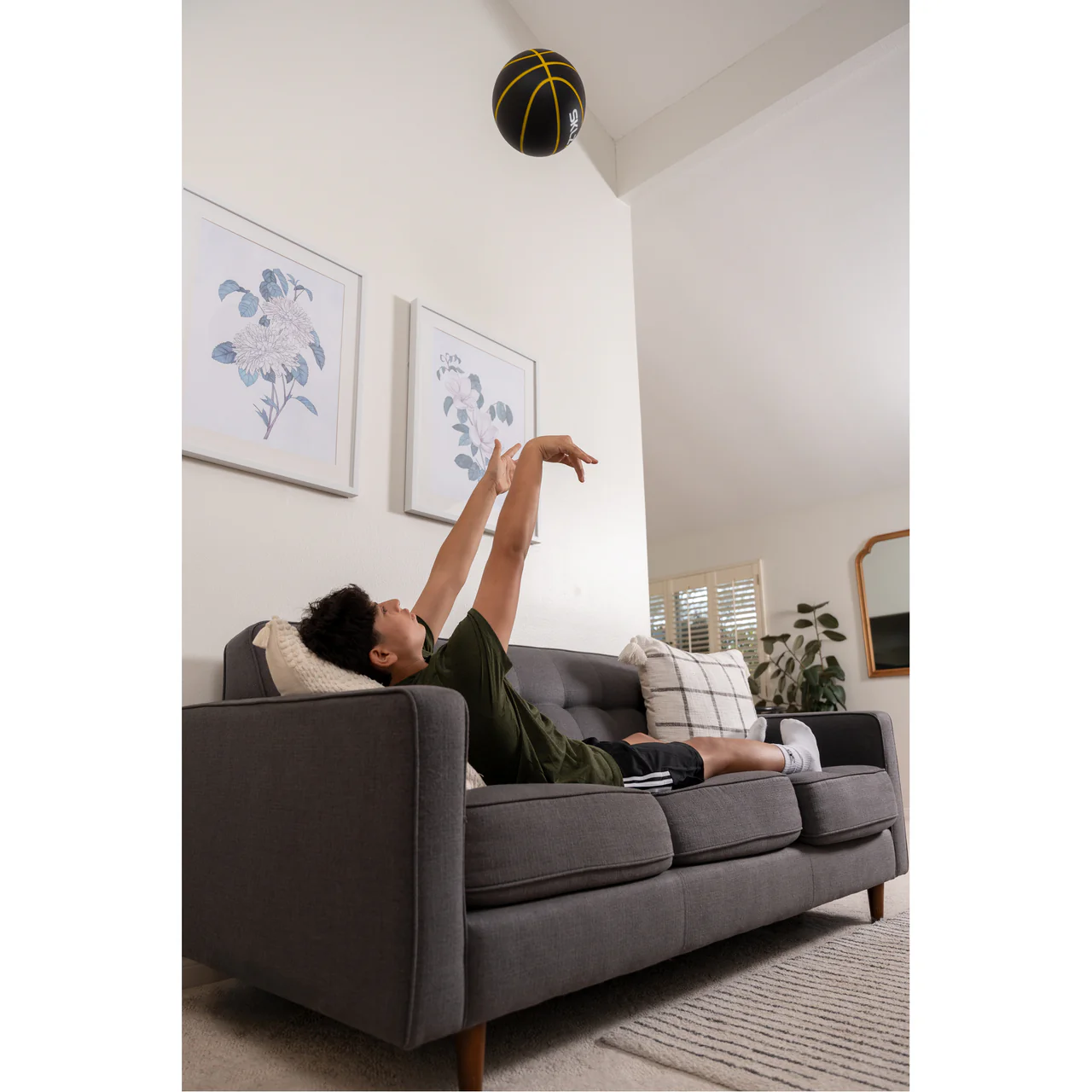SKLZ BASHHHKETBALL PRO FES SIOC BASKETBALL - lifestyle view, player shooting ball from sofa indoors